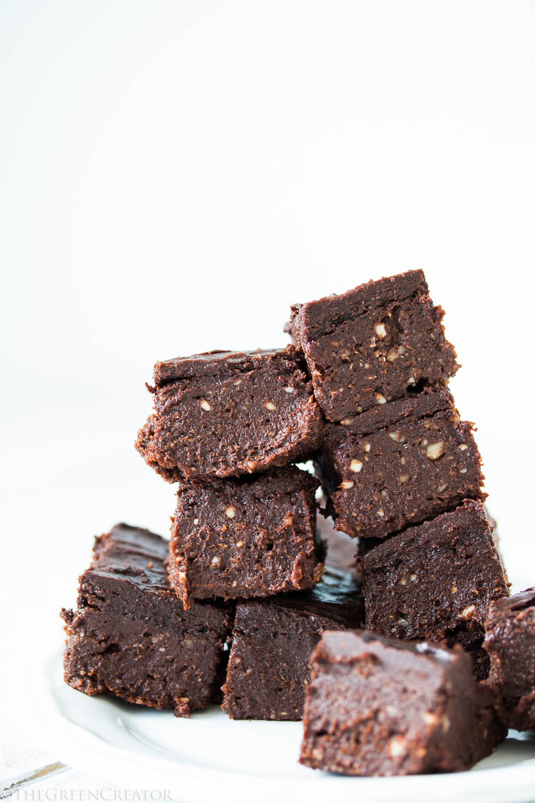 chocolate brownies with frosting stacked with a white backdrop