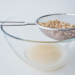 soaked oats in a strainer draining above a bowl