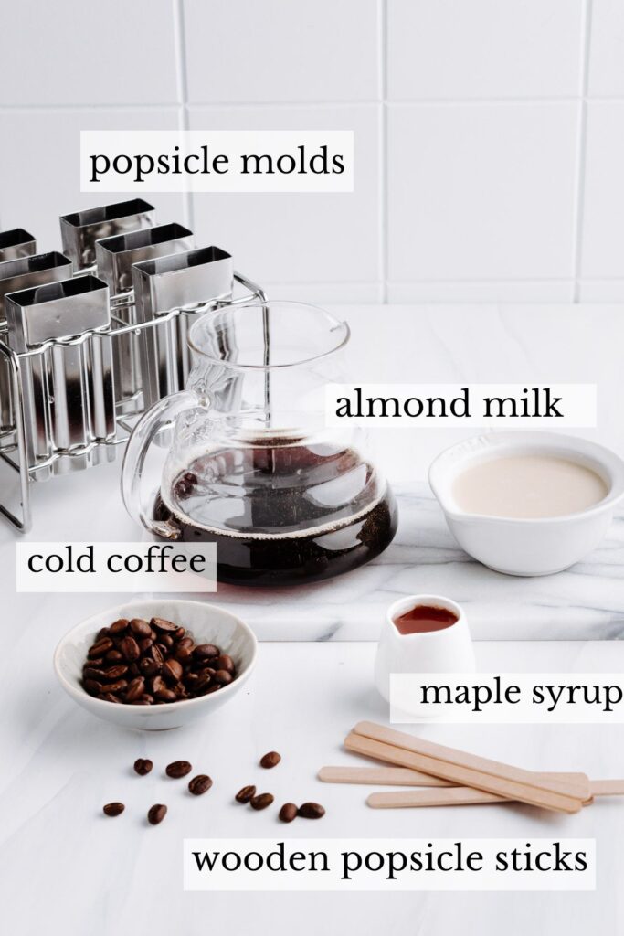 Ingredients and equipment for coffee popsicles on a white backdrop with the names next to it