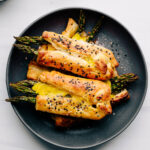 Asparagus with Puff Pastry piled on each other on a round black plate on a white backdrop
