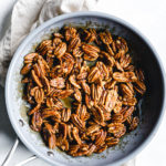 sticky cooked candied pecans in blue skillet on a beige napkin