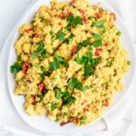 The best vegan scrambled tofu eggs on a white plate garnished with fresh parsley.